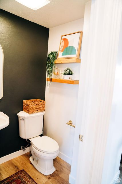 Bathroom featuring toilet, wood finished floors, and baseboards