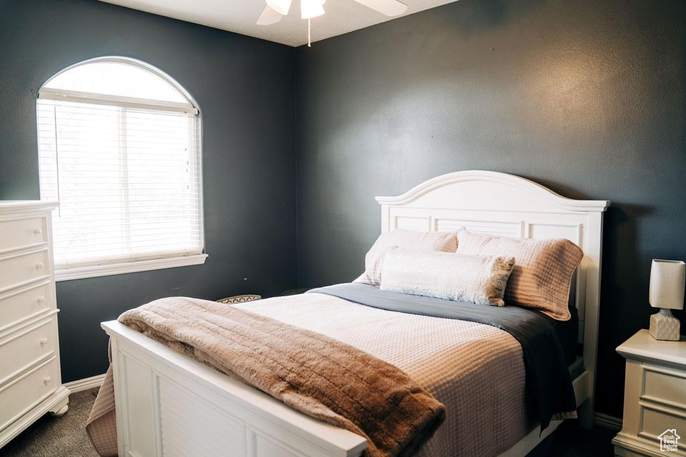 Bedroom featuring a ceiling fan and dark carpet