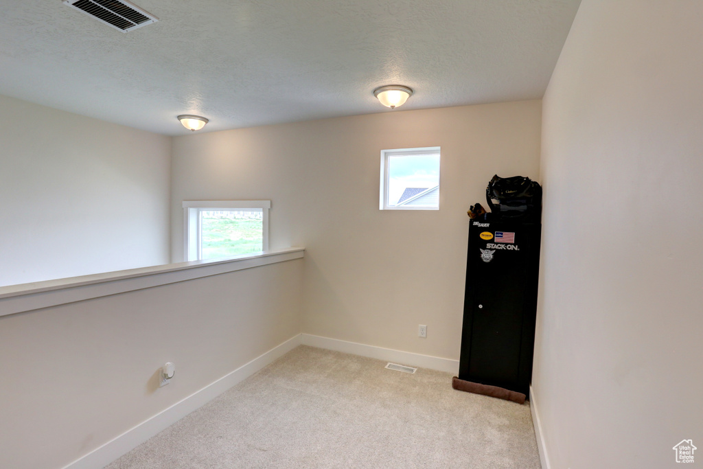 Empty room featuring light colored carpet, visible vents, and baseboards