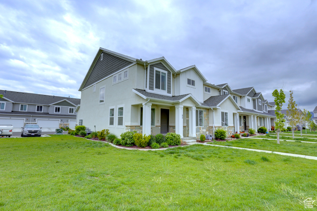 View of front of house with covered porch, stucco siding, a residential view, stone siding, and a front lawn