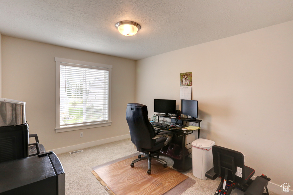 Carpeted office featuring a textured ceiling, baseboards, and visible vents