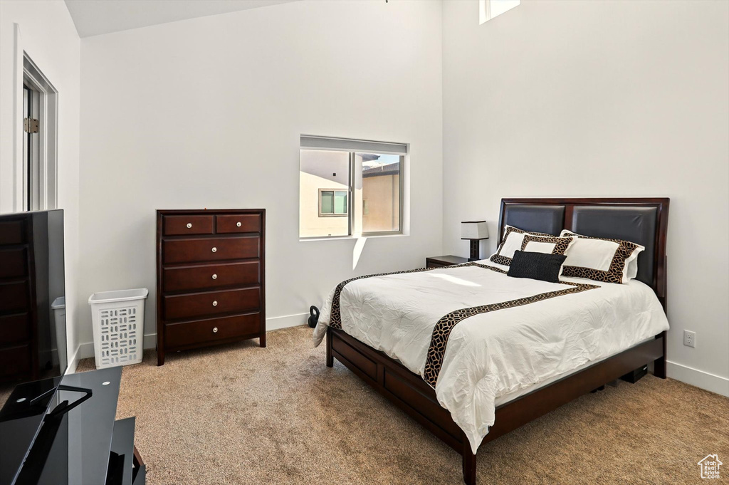 Carpeted bedroom with a towering ceiling and baseboards