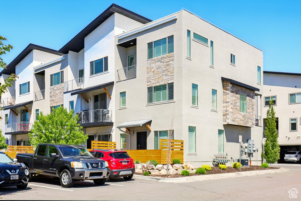 View of building exterior with central AC and uncovered parking