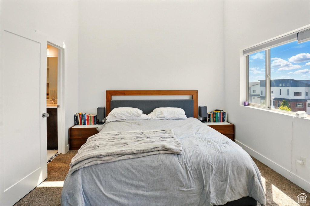 Carpeted bedroom featuring a high ceiling and baseboards