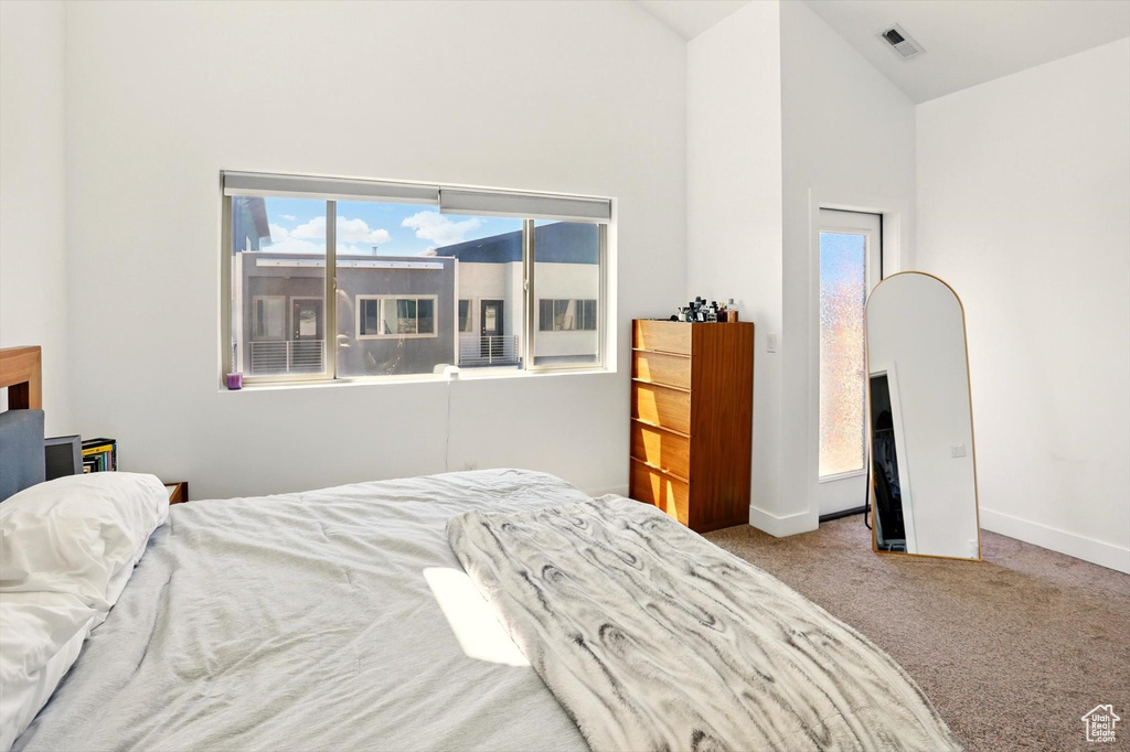 Bedroom with baseboards, carpet floors, high vaulted ceiling, and visible vents