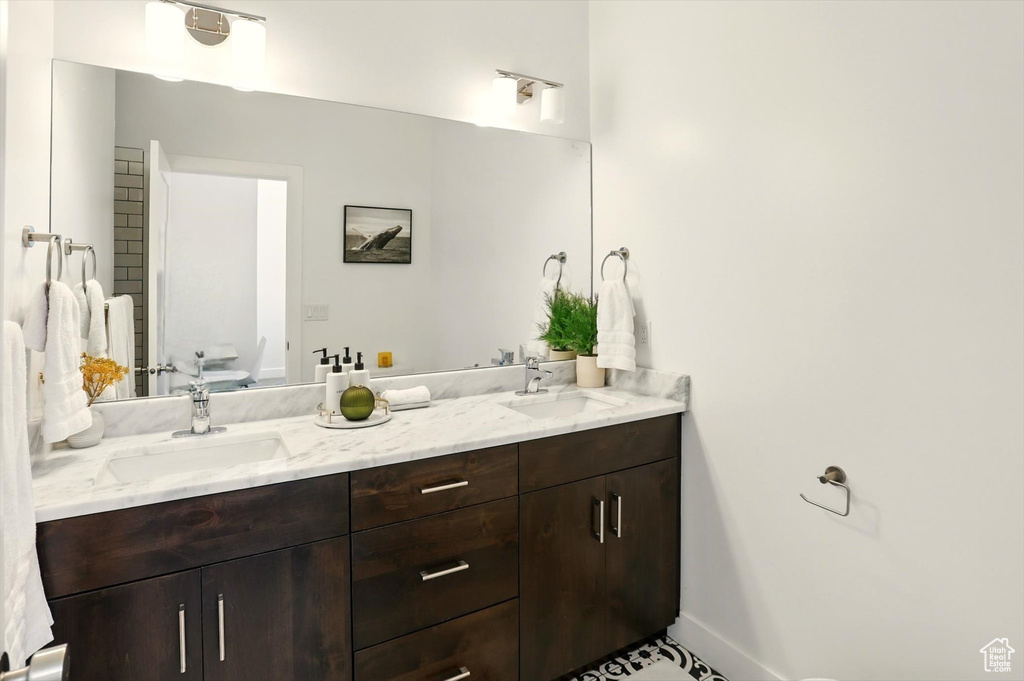 Bathroom featuring a sink, double vanity, toilet, and baseboards