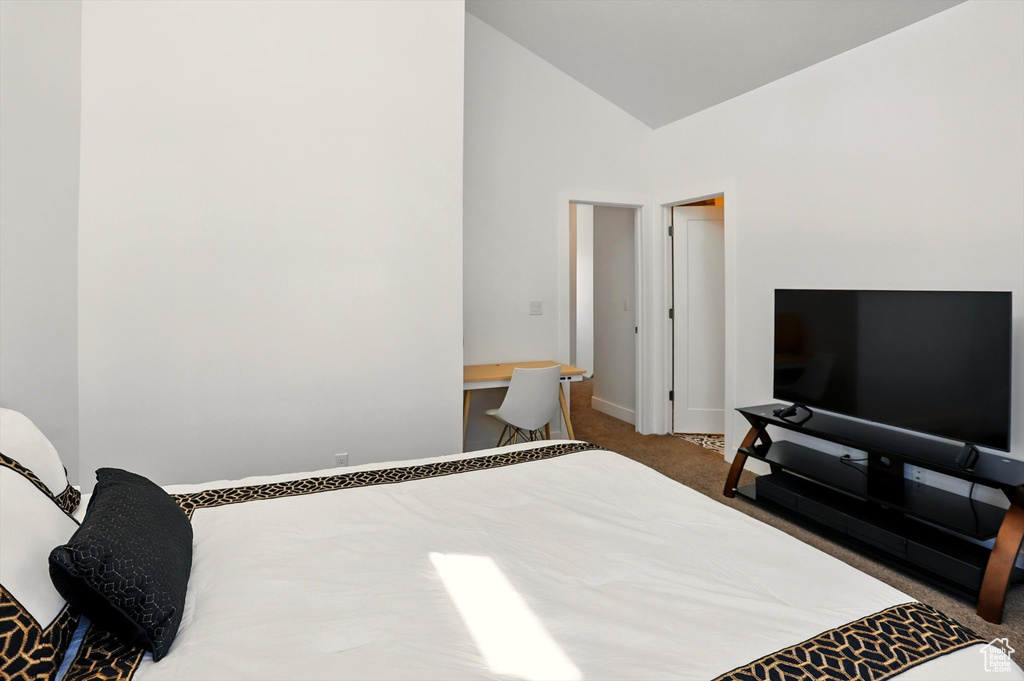 Carpeted bedroom featuring vaulted ceiling and baseboards