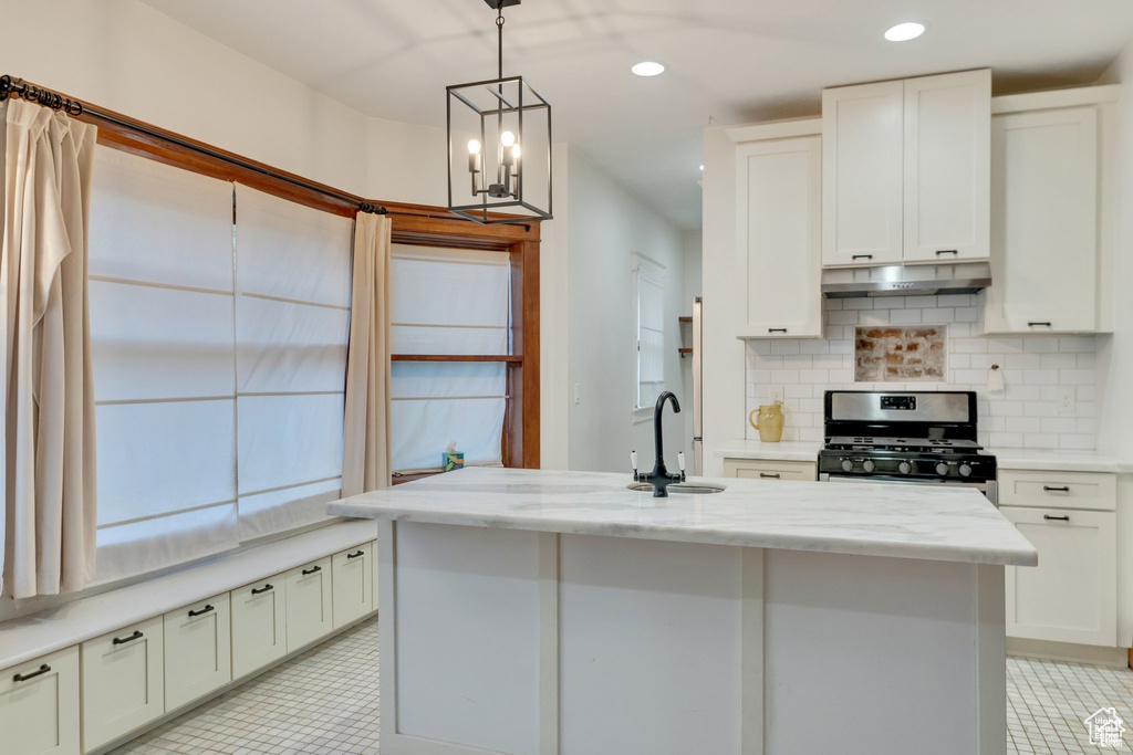 Kitchen featuring decorative backsplash, stainless steel range with gas stovetop, light tile patterned flooring, and a sink