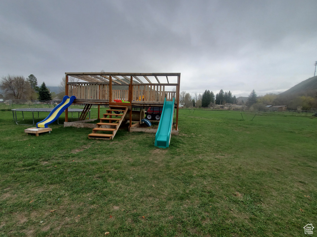 View of play area with a yard and fence