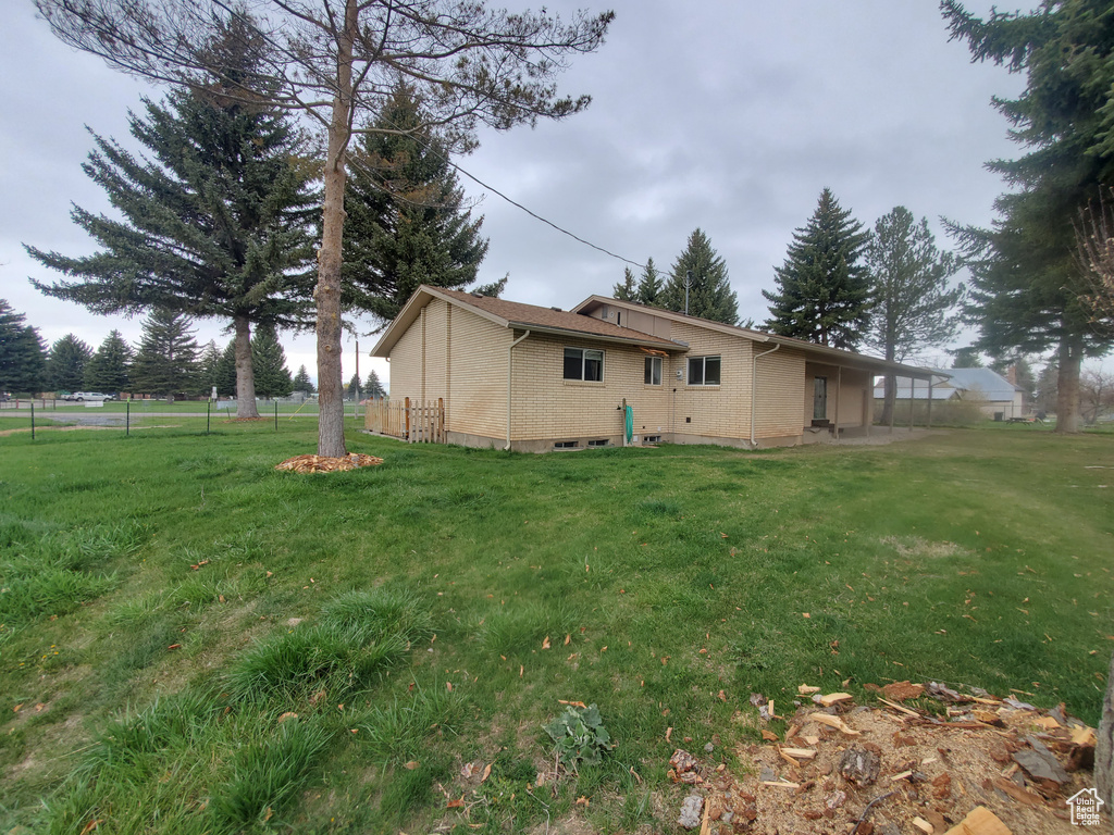 Rear view of property with brick siding, a yard, and fence