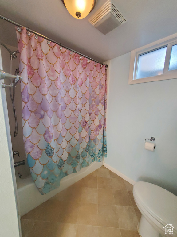 Bathroom featuring toilet, shower / tub combo with curtain, visible vents, tile patterned floors, and baseboards