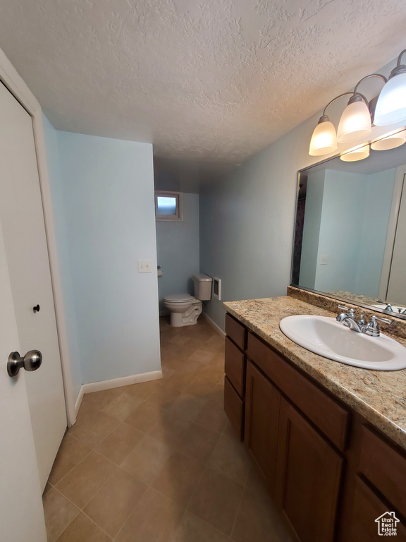 Bathroom with toilet, baseboards, vanity, and a textured ceiling