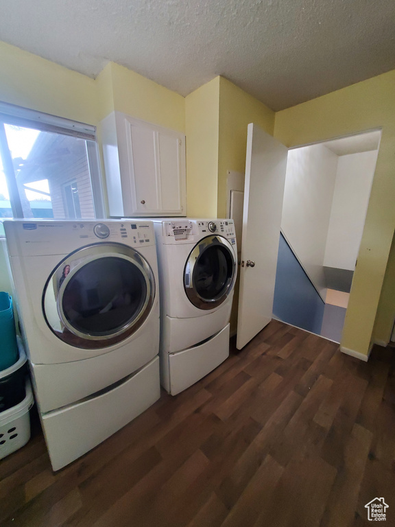 Clothes washing area featuring separate washer and dryer, a textured ceiling, laundry area, and dark wood-style floors