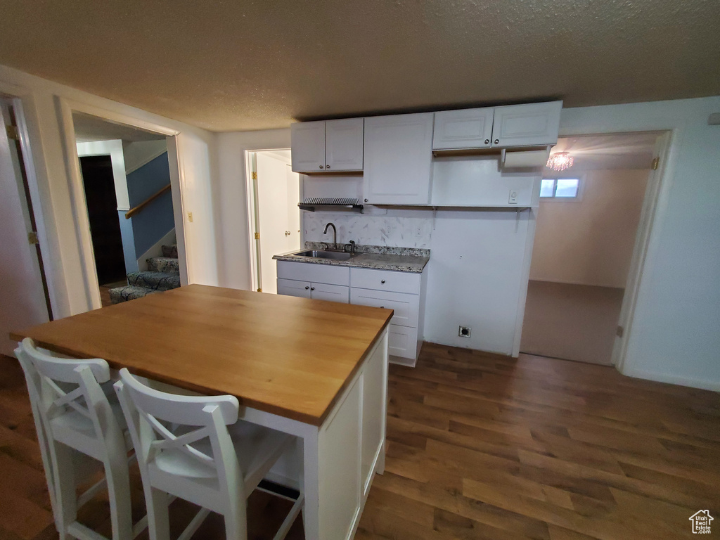 Kitchen with wood counters, white cabinetry, dark wood-style flooring, and a sink