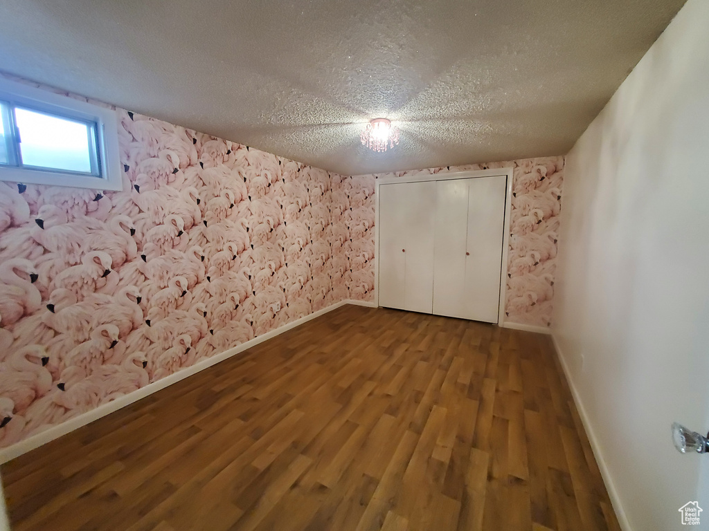 Unfurnished bedroom with a textured ceiling, baseboards, and wood finished floors