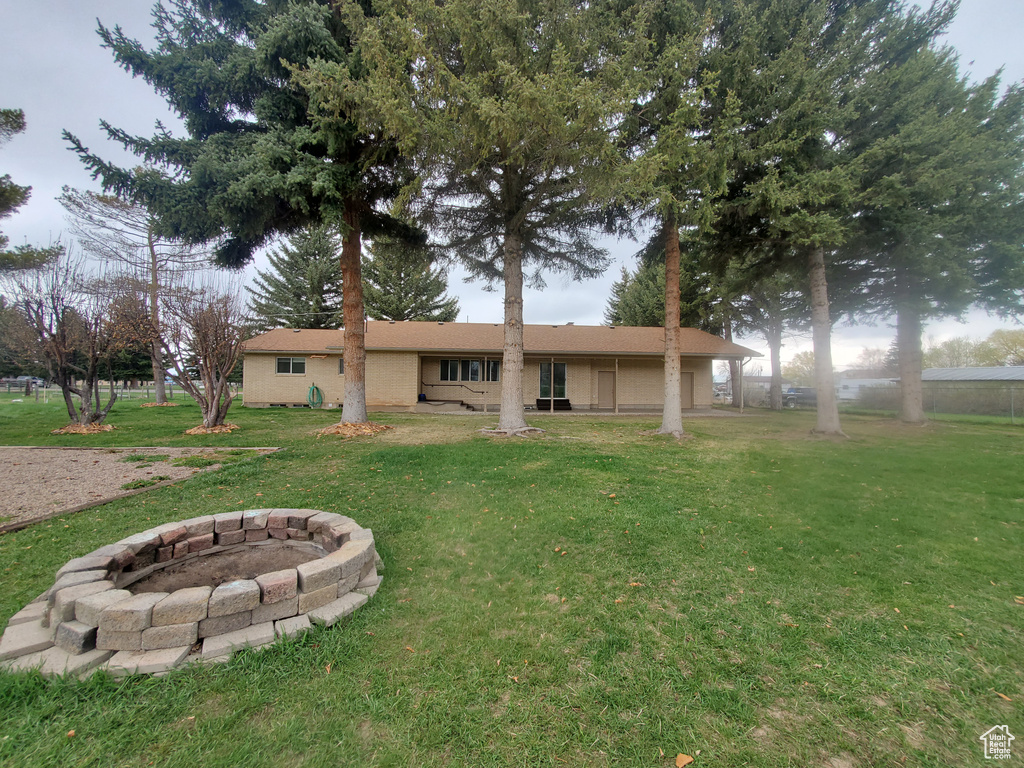 Back of house featuring an outdoor fire pit and a lawn