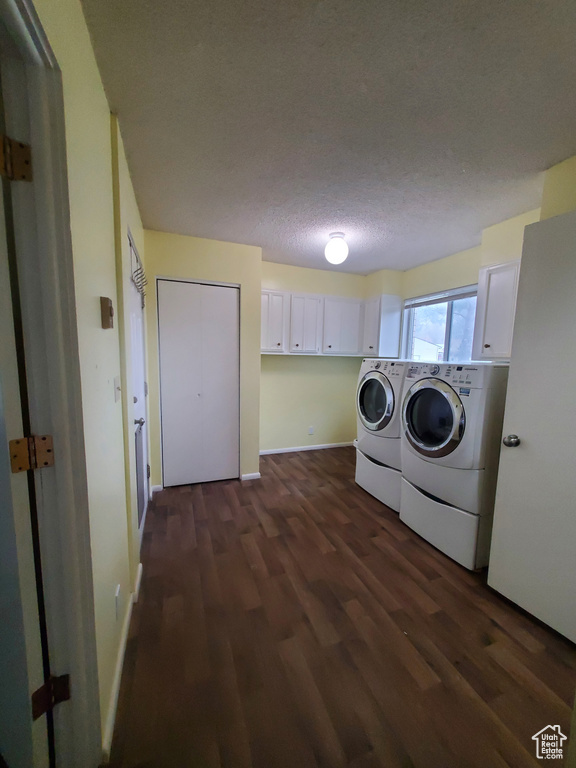 Laundry room featuring cabinet space, a textured ceiling, dark wood-type flooring, washing machine and dryer, and baseboards