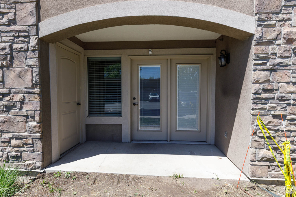 Property entrance with stone siding, stucco siding, and a patio area