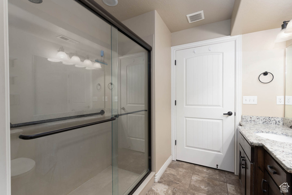 Full bath featuring a shower stall, vanity, and visible vents