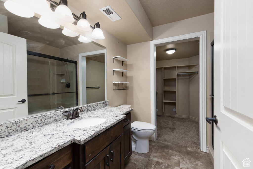 Bathroom with a stall shower, toilet, visible vents, vanity, and a walk in closet