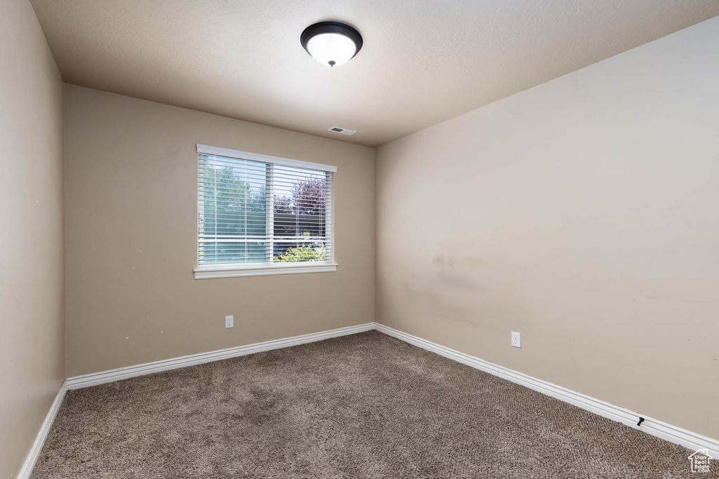 Spare room featuring baseboards, carpet flooring, and visible vents