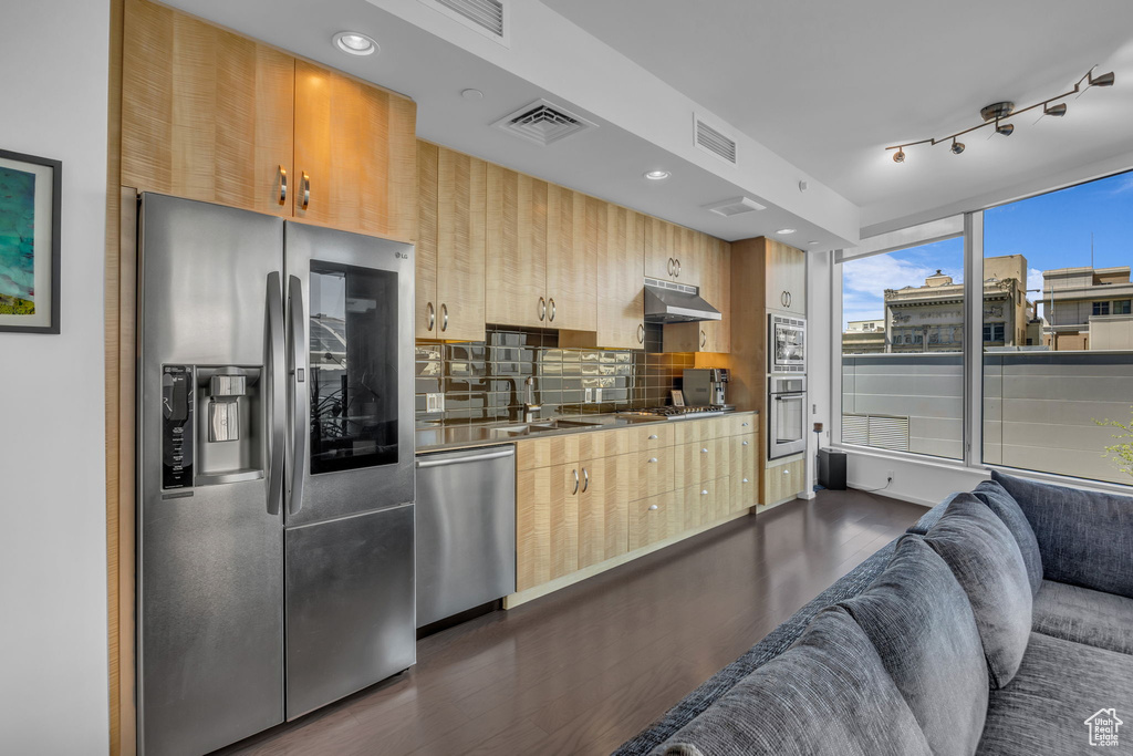 Kitchen with light brown cabinetry, dark wood-style floors, visible vents, and appliances with stainless steel finishes