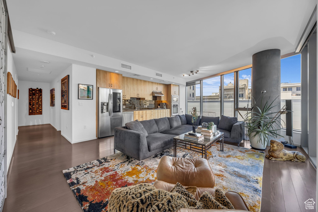 Living room with dark wood-type flooring, baseboards, and visible vents