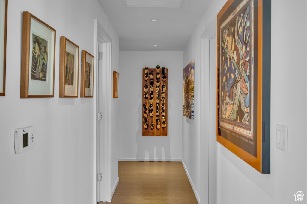 Corridor with wood finished floors, baseboards, and recessed lighting