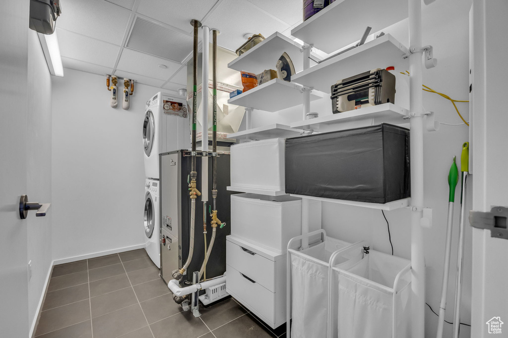 Clothes washing area featuring baseboards, tile patterned flooring, laundry area, and stacked washer / drying machine