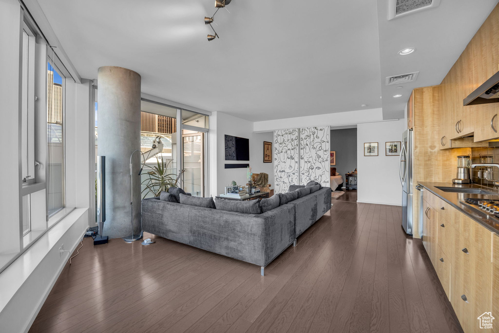 Living area with dark wood finished floors, visible vents, and a wall of windows