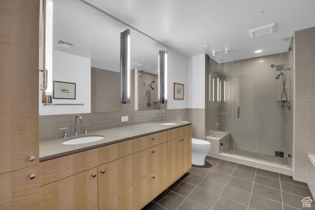 Bathroom with toilet, tile patterned flooring, a stall shower, and a sink