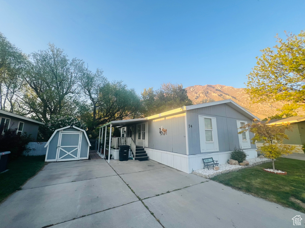 View of side of home featuring covered porch, a storage shed, a mountain view, and an outbuilding