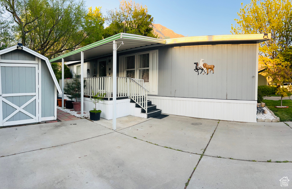 Manufactured / mobile home with covered porch, an outbuilding, a patio, and a shed