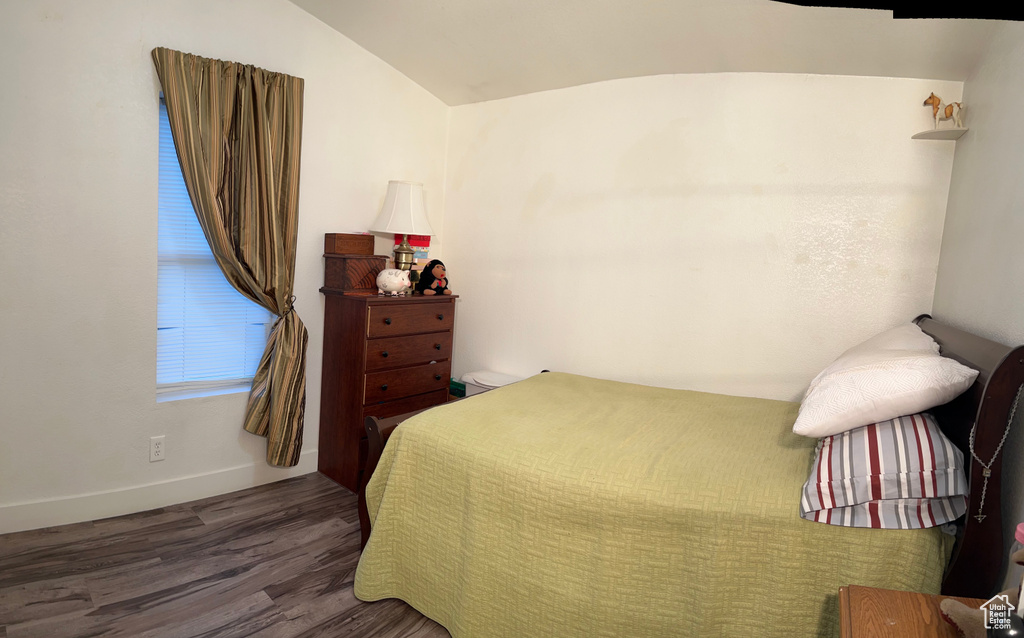 Bedroom featuring vaulted ceiling, baseboards, and wood finished floors