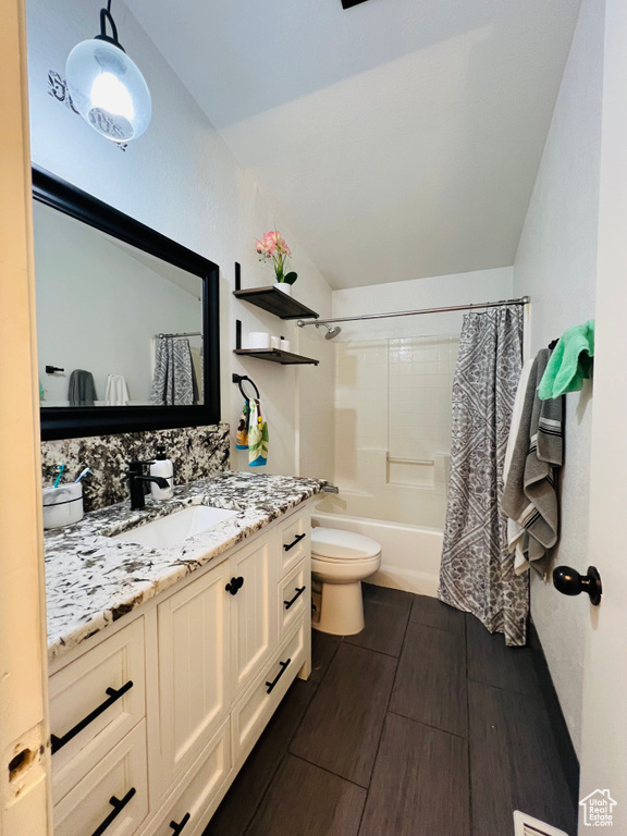 Full bath with toilet, wood finished floors, vanity, shower / bath combo, and vaulted ceiling