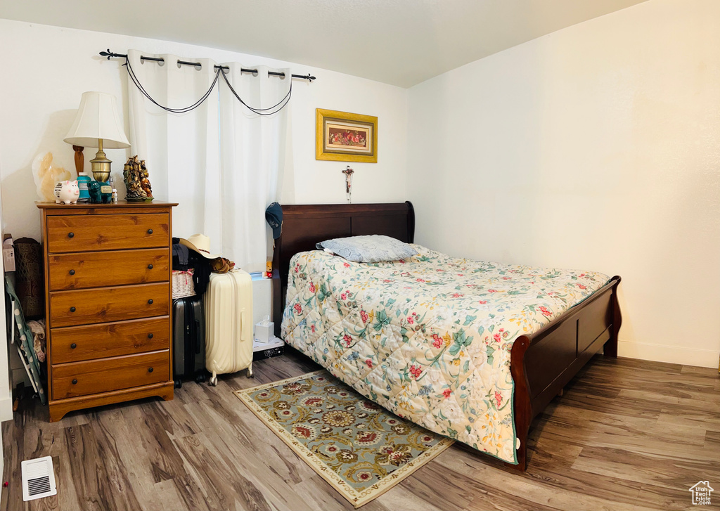 Bedroom with visible vents, wood finished floors, and baseboards