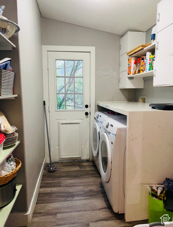 Clothes washing area featuring washing machine and dryer, cabinet space, dark wood-style floors, and baseboards