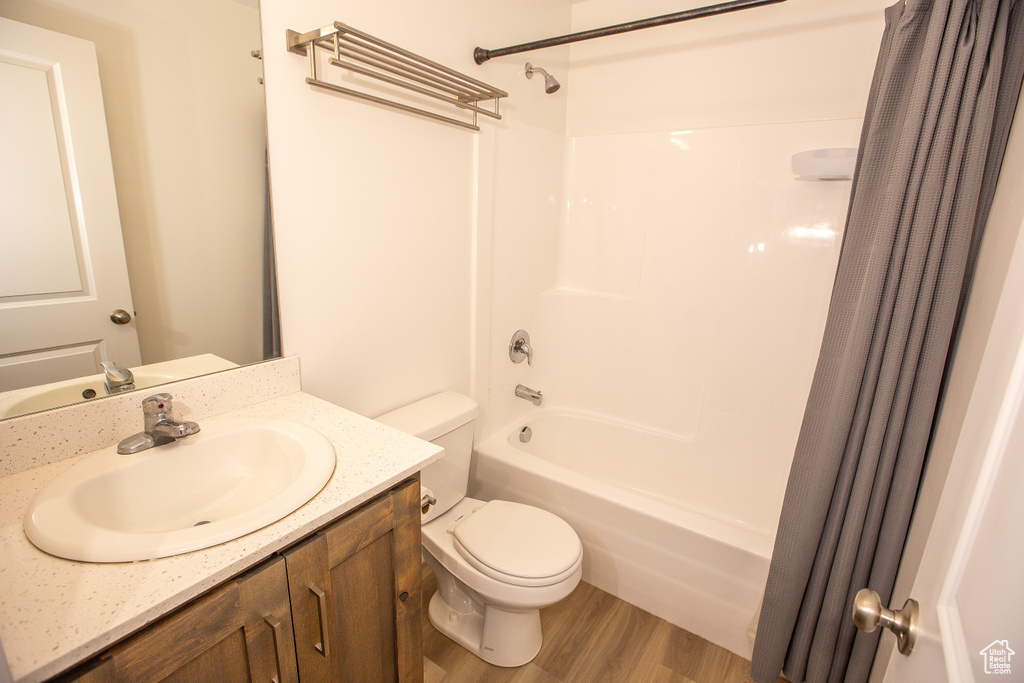Full bathroom featuring toilet, shower / tub combo, wood finished floors, and vanity