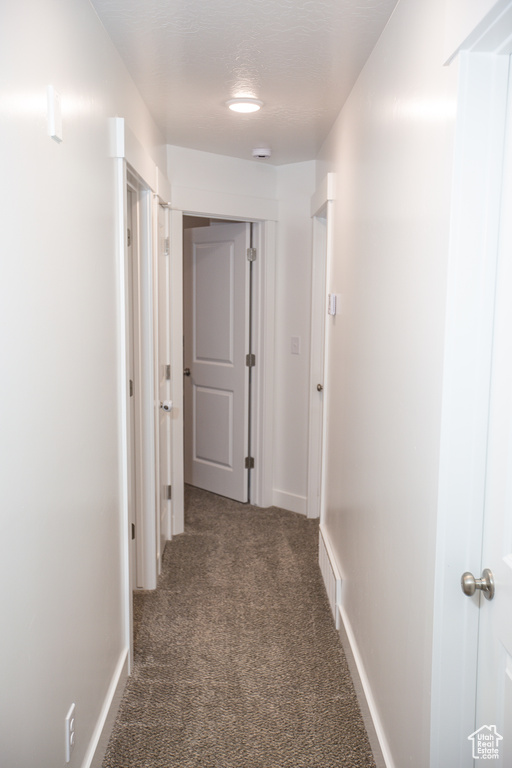 Hall with baseboards, carpet flooring, and visible vents