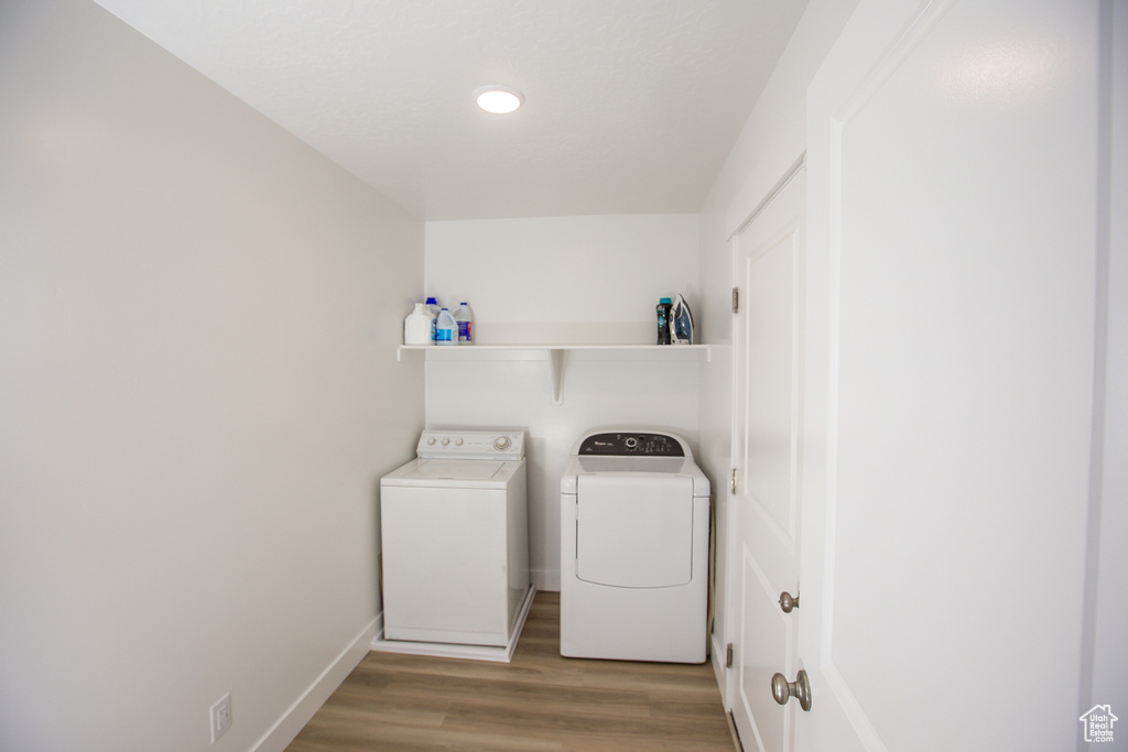 Laundry area featuring recessed lighting, baseboards, wood finished floors, washing machine and clothes dryer, and laundry area