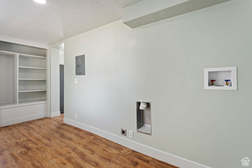Washroom featuring wood finished floors, baseboards, a textured ceiling, electric panel, and washer hookup