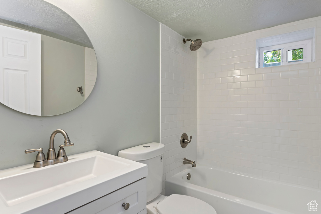 Full bath featuring vanity, a textured ceiling, shower / bathing tub combination, and toilet