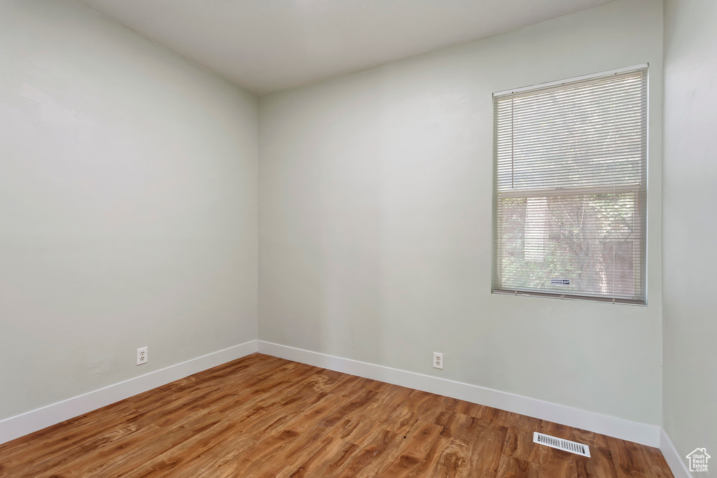 Empty room featuring visible vents, light wood-style flooring, and baseboards