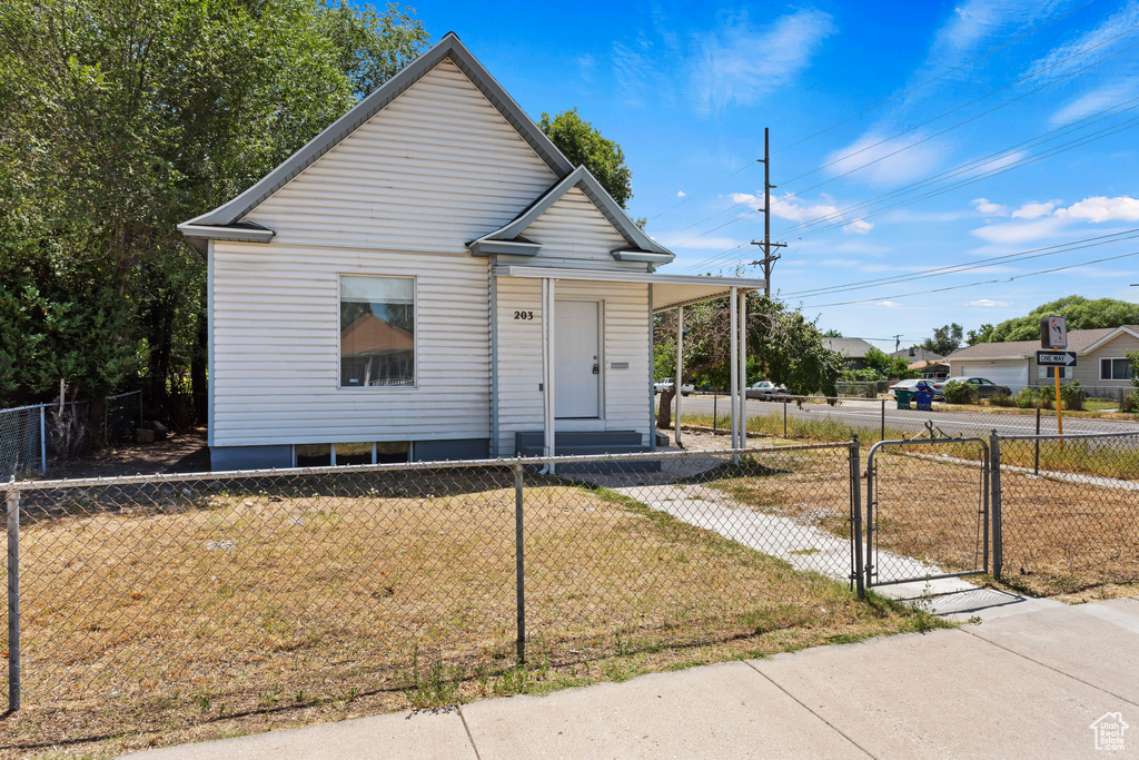 Bungalow with a porch, a fenced front yard, a gate, and a front yard