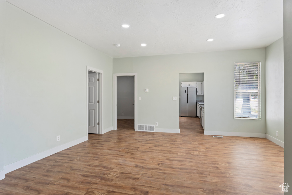 Unfurnished living room featuring baseboards, recessed lighting, wood finished floors, and visible vents