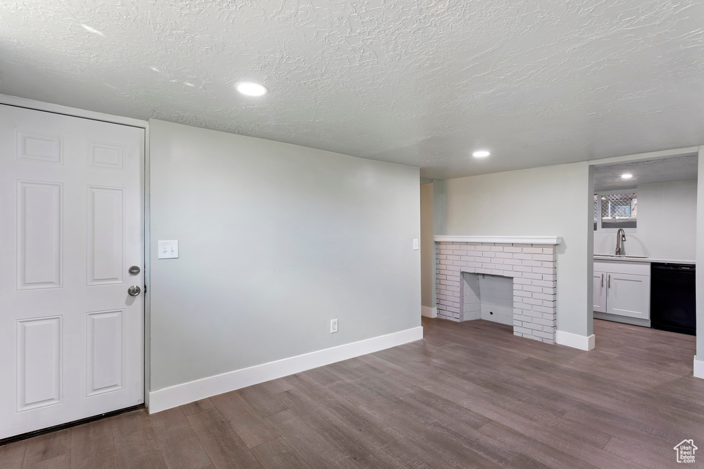 Unfurnished living room with baseboards, a sink, a textured ceiling, and wood finished floors
