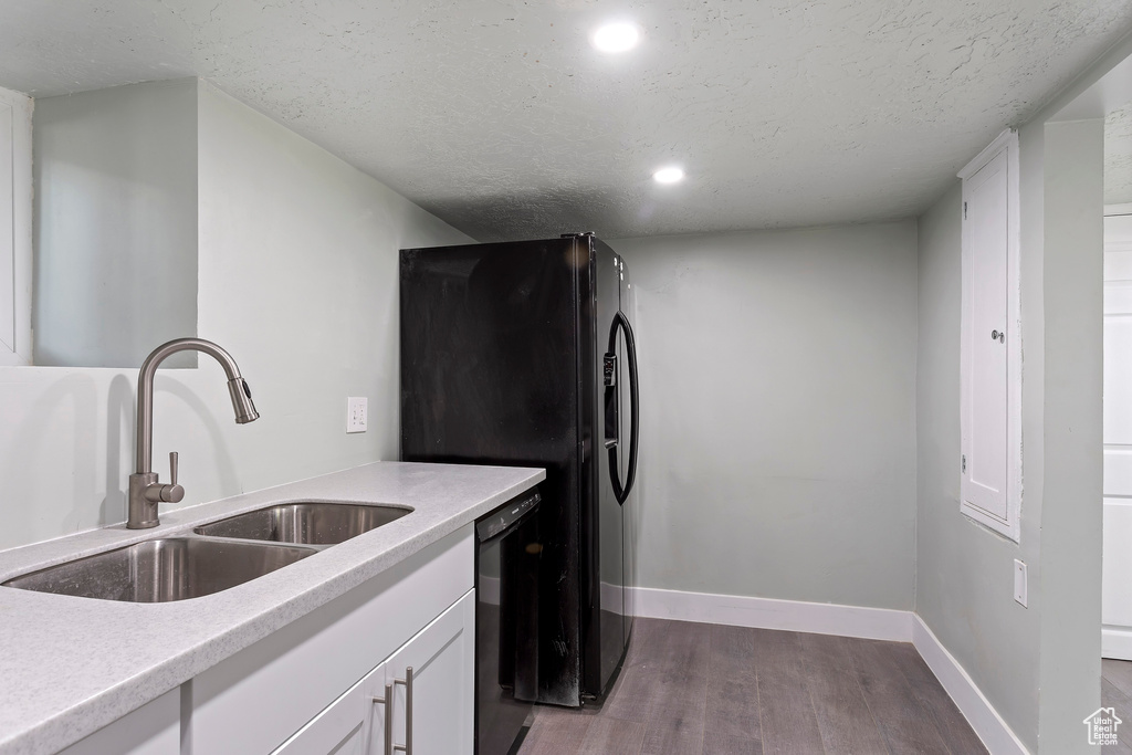 Kitchen with a sink, baseboards, black appliances, and wood finished floors