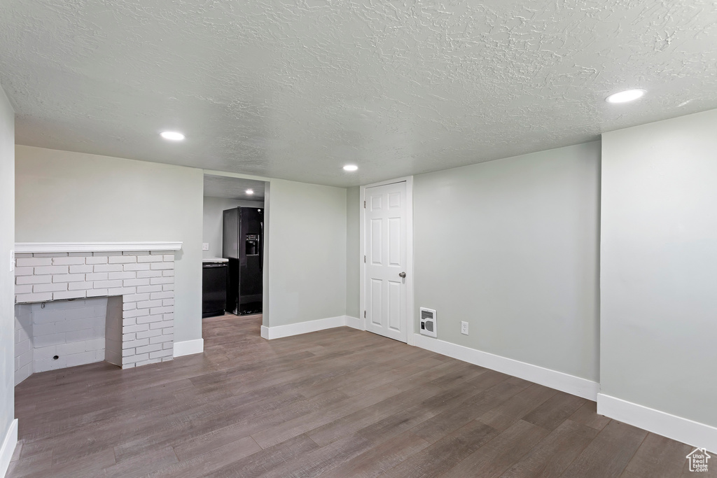 Unfurnished living room featuring a textured ceiling, recessed lighting, baseboards, wood finished floors, and visible vents