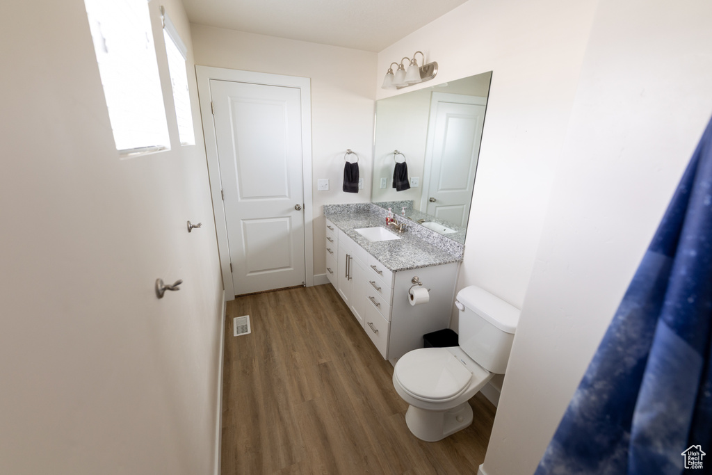 Bathroom with toilet, visible vents, wood finished floors, and vanity