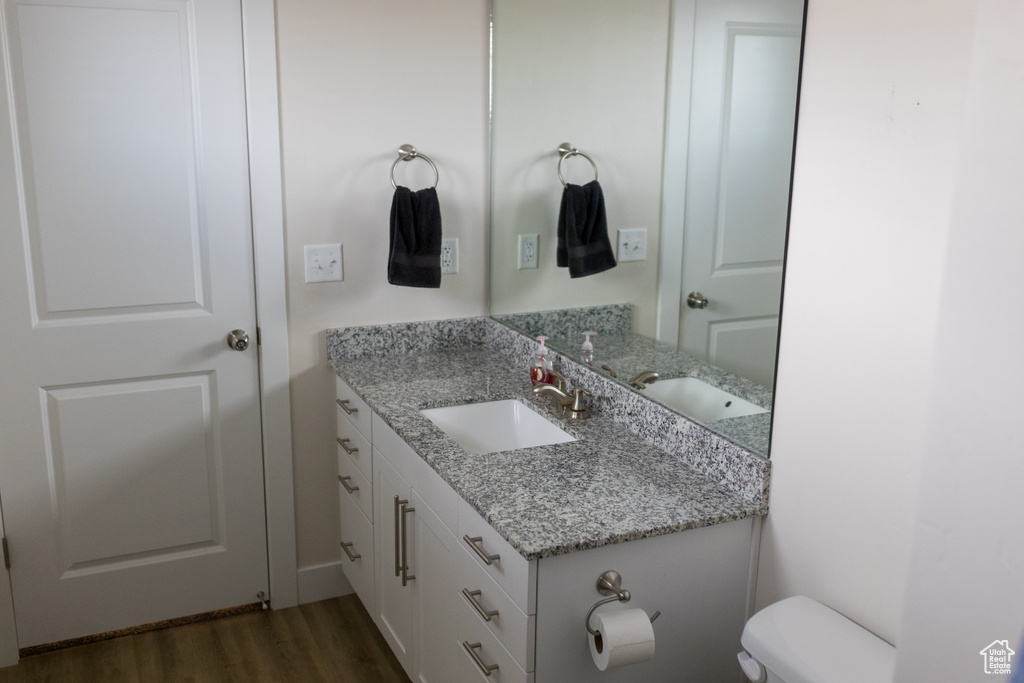Half bathroom with toilet, wood finished floors, and vanity